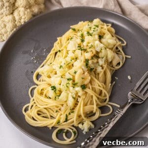 spaghetti with cauliflower plated on a dish garnished with parsley.
