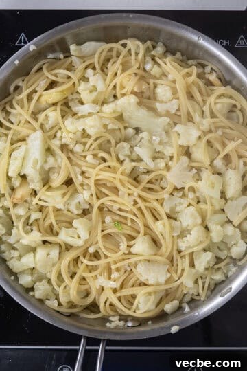 Roasted Cauliflower Pasta with Garlic and Parmesan 7 spaghetti added to pan with cauliflower and garlic.