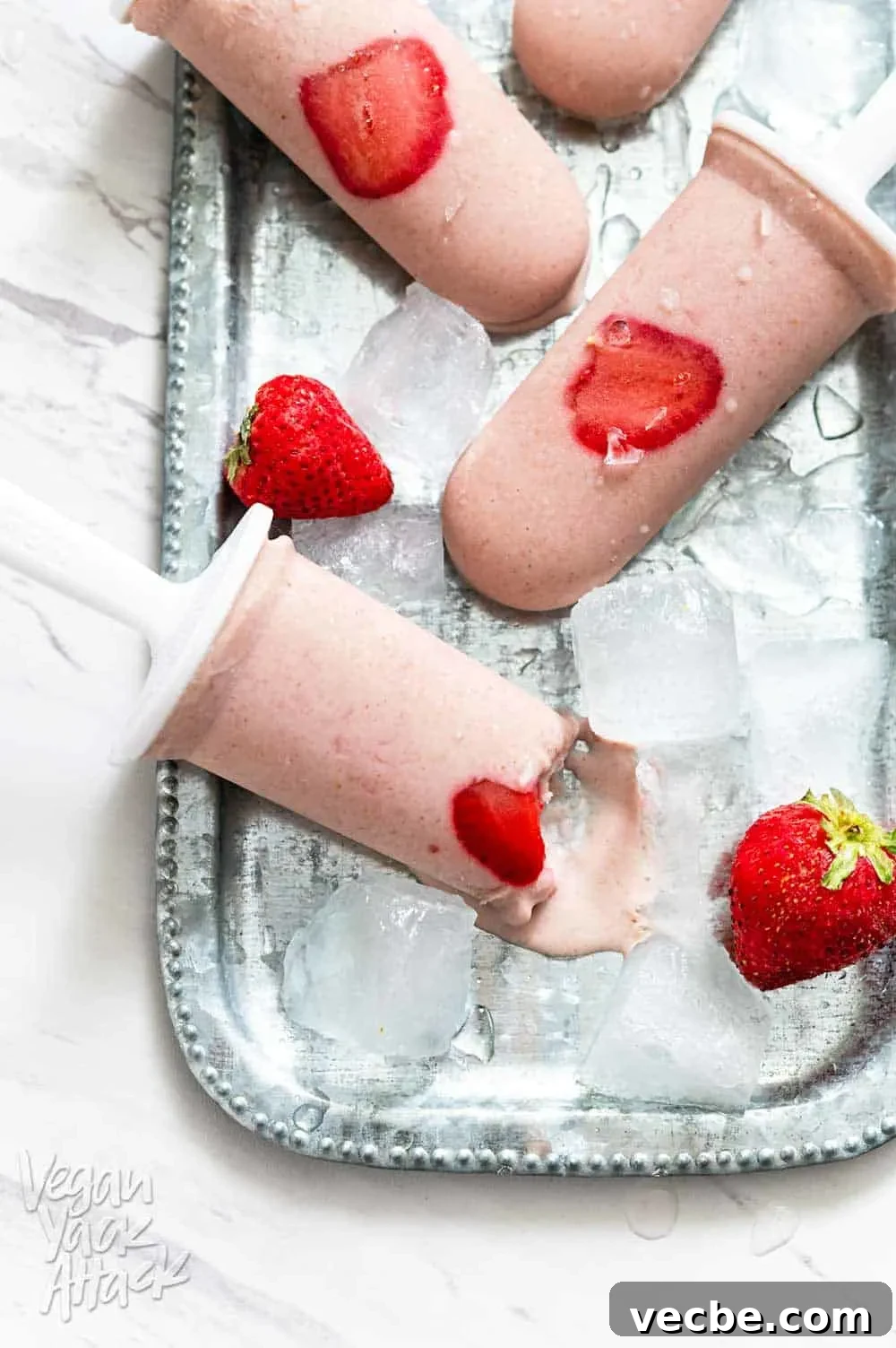 Creamy Strawberry Oat Milk Popsicles Recipe 6 Strawberry Oat Milk Popsicles on a metal platter with ice cubes