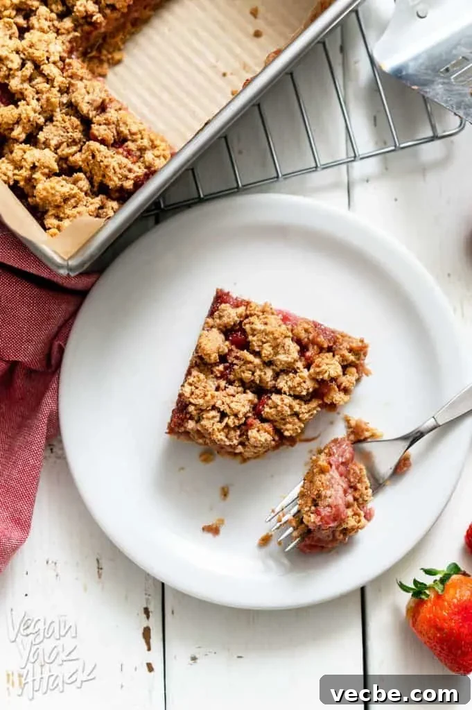 Creamy Strawberry Oat Milk Popsicles Recipe 9 Piece of strawberry crumble bar cut out of a baking pan and bite on a fork next to it