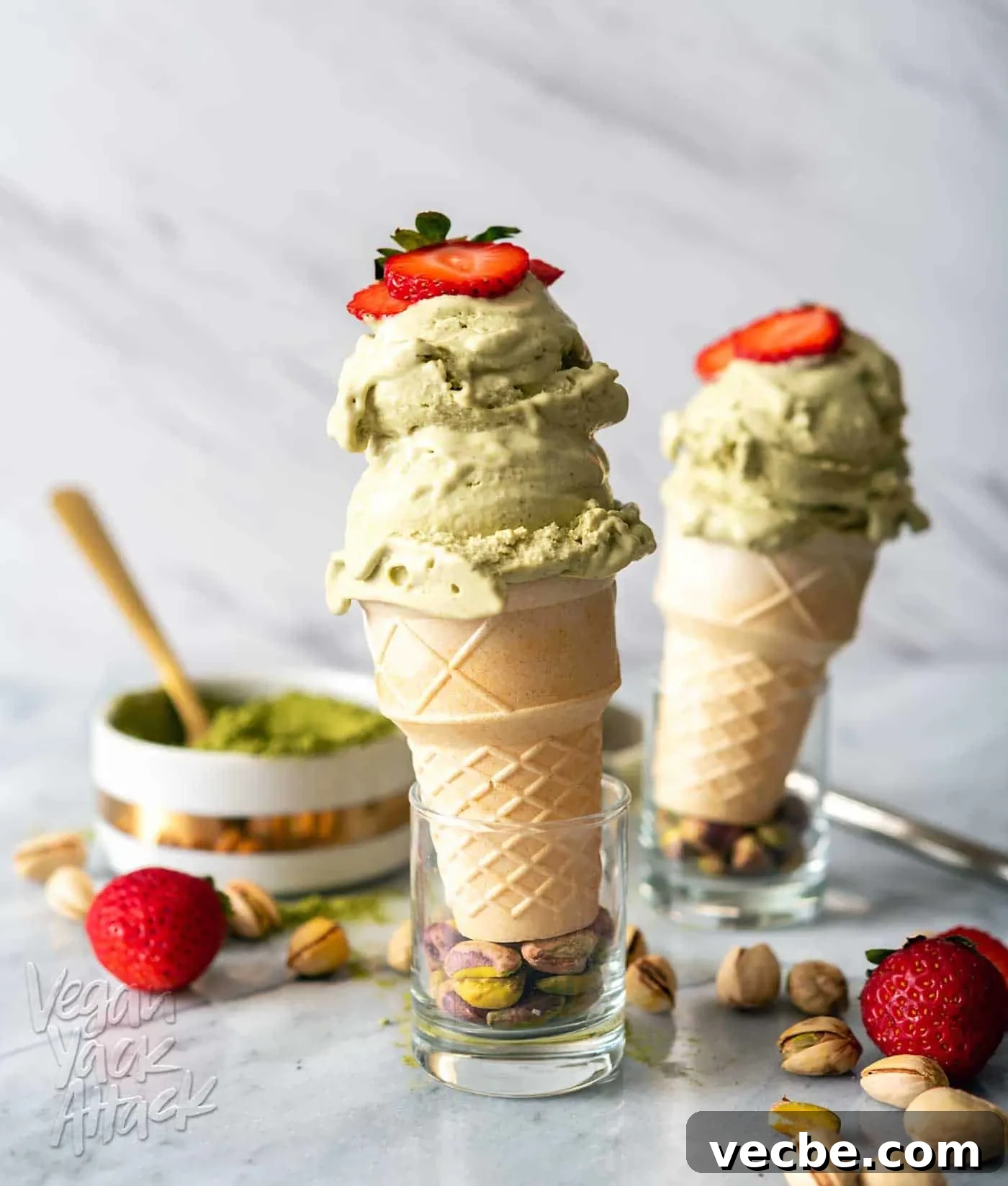 Creamy Strawberry Oat Milk Popsicles Recipe 10 Image of two cones of pistachio matcha ice cream on a marble counter top