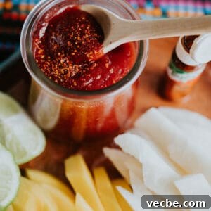 How to Make Mexican Chamoy Sauce at Home 15 Homemade chamoy recipe by Yvette Marquez-Sharpnack of Muy Bueno, a sweet, sour, spicy Mexican chamoy sauce served in a jar with a wooden spoon, topped with chile lime seasoning and paired with fresh mango and jicama.