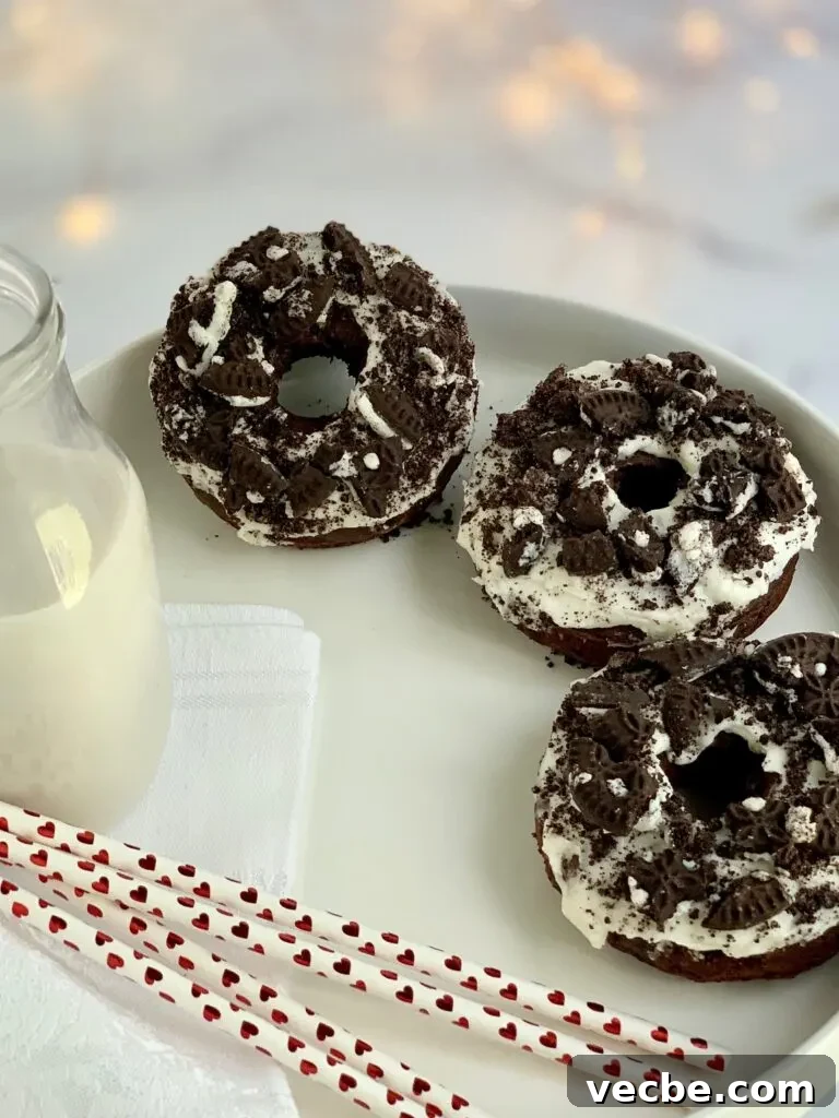 Romantic Valentine's Day Recipes for Two 11 3 oreo donuts with a creamy white frosting and oreo crumbs sprinkled on top next to a glass of milk and 3 straws with red hearts on them.