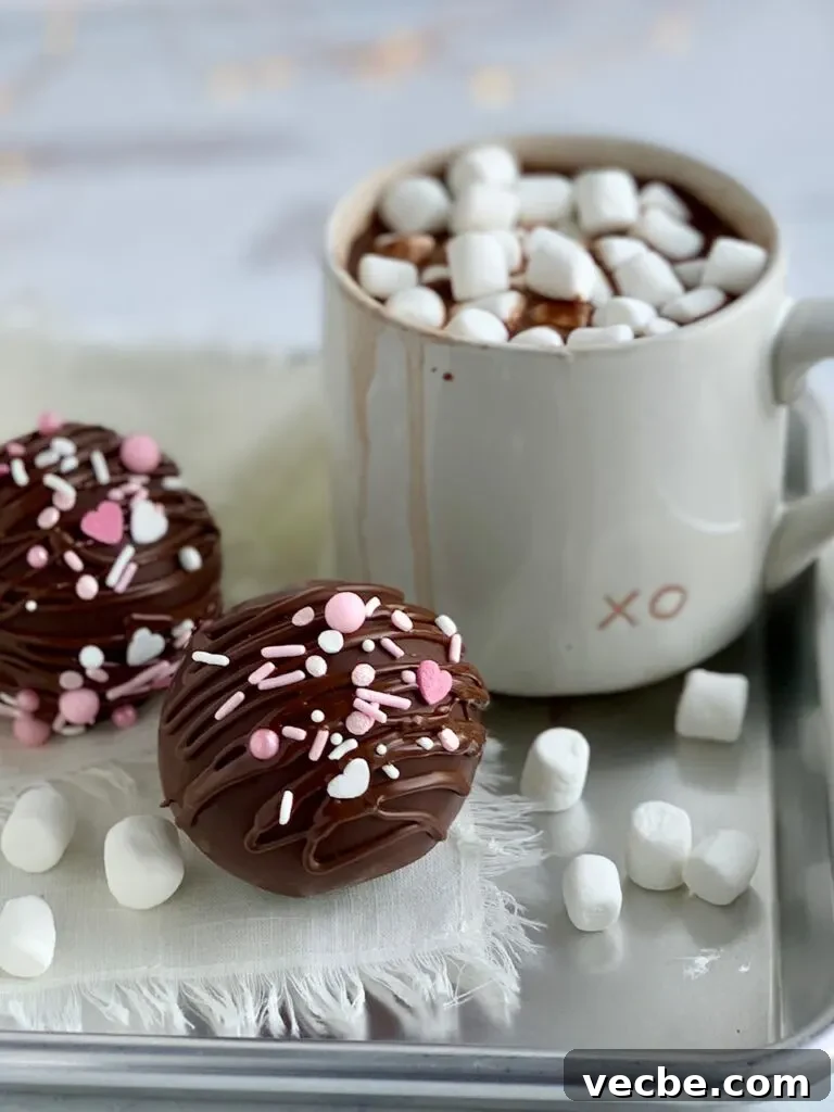 Romantic Valentine's Day Recipes for Two 13 2 hollow chocolate balls filled with hot chocolate mix and sprinkles then decorated with drizzled chocolate on the outside and white and pink sprinkles. All next to a mug of hot chocolate.
