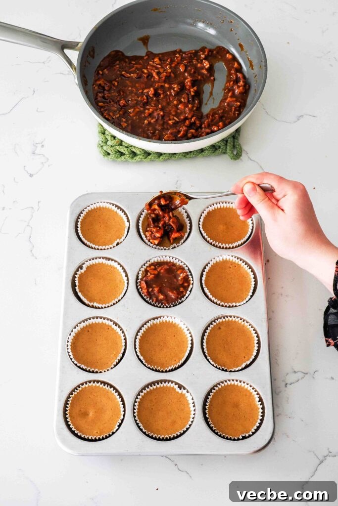 Mini Pecan Pie Cheesecake Bites Recipe 17 A spoon tops a mini pecan pie cheesecake with caramel pecan topping.