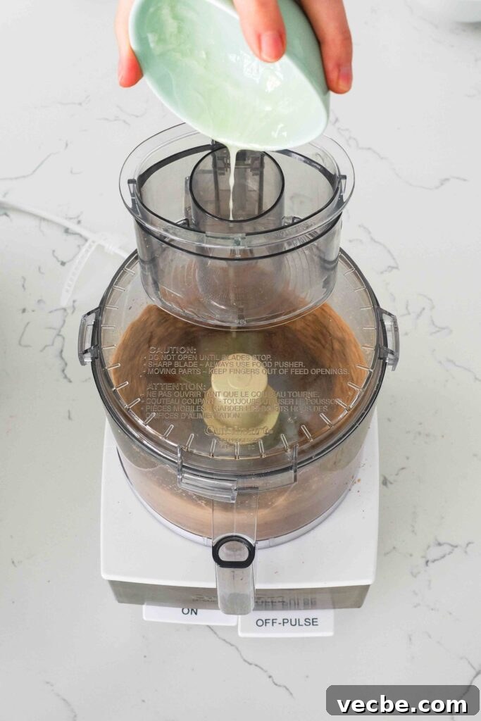 Mini Pecan Pie Cheesecake Bites Recipe 4 Melted butter is streamed into a food processor with crushed graham crackers and pecans.