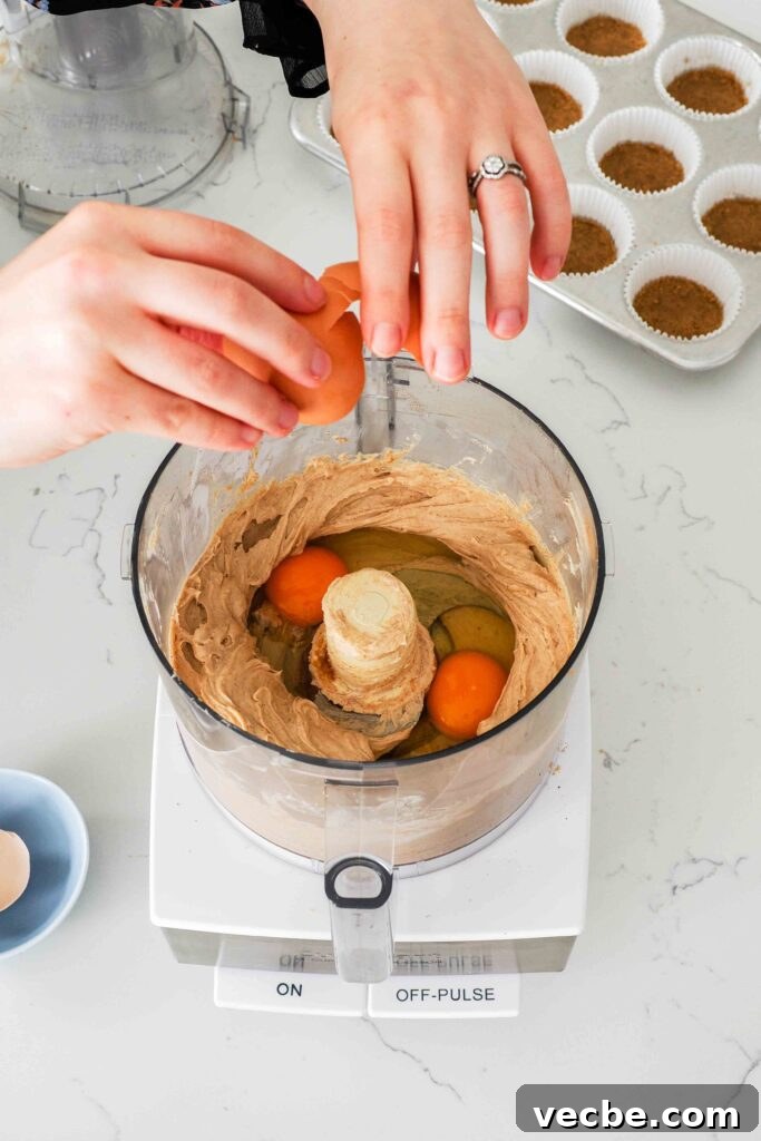 Mini Pecan Pie Cheesecake Bites Recipe 8 Two hands crack an egg into a food processor bowl with smooth brown sugar cinnamon cheesecake filling.
