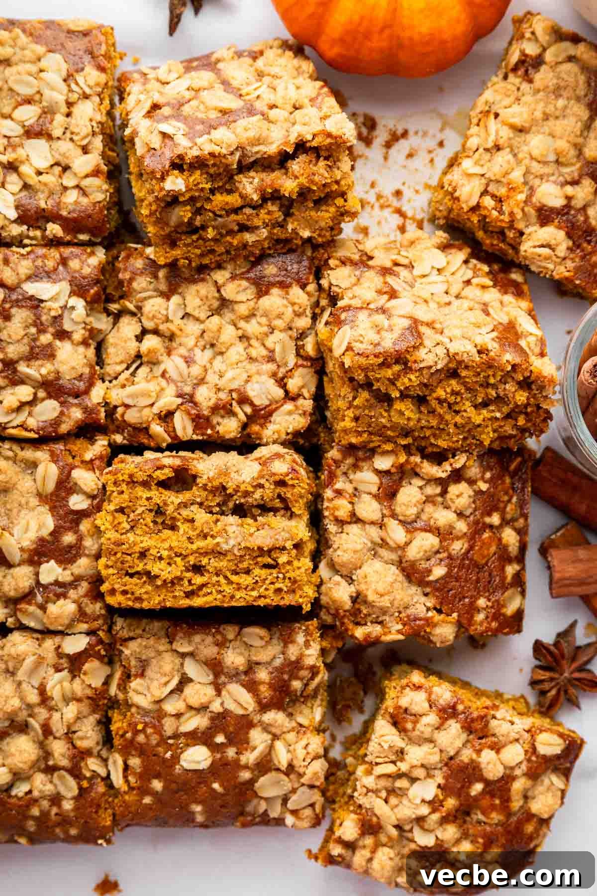 Pumpkin Coffee Cake Recipe with Cinnamon Streusel 2 Squares of pumpkin coffee cake on table with a mini pumpkin.