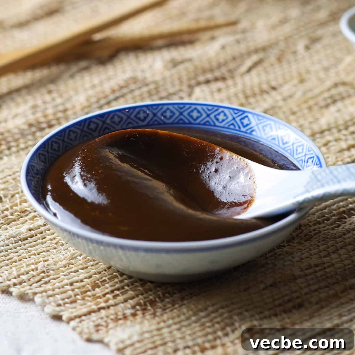 Quick Chinese Pickled Cucumbers Recipe 13 Close-up photo of a shallow Chinese bowl filled with homemade hoisin sauce and a Chinese ceramic spoon.