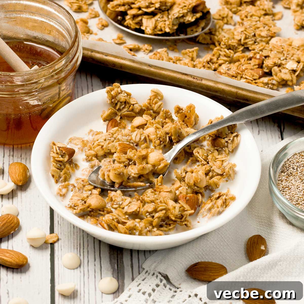 White Chocolate Vanilla Almond Granola 2 Vanilla almond granola with white chocolate chips and a small white bowl with a spoon.