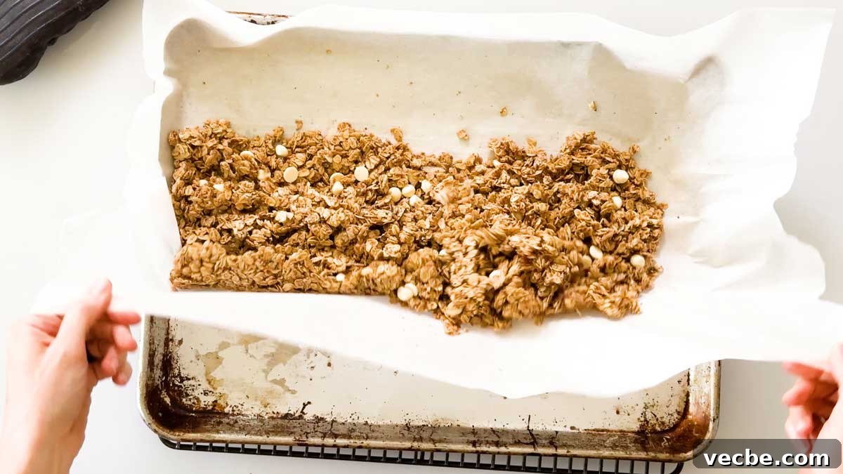 White Chocolate Vanilla Almond Granola 11 Lifting the sides of the parchment paper to redistribute the granola.