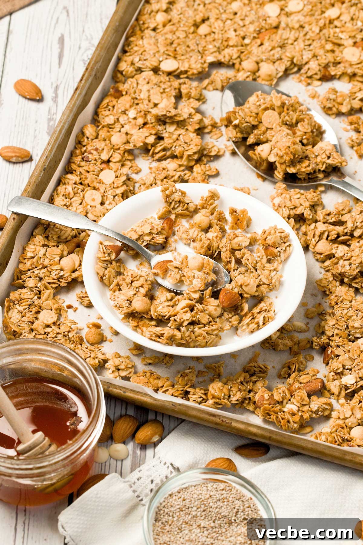 White Chocolate Vanilla Almond Granola 12 A close-up of a small white bowl with vanilla almond granola and white chocolate chips in milk on a cookie sheet.