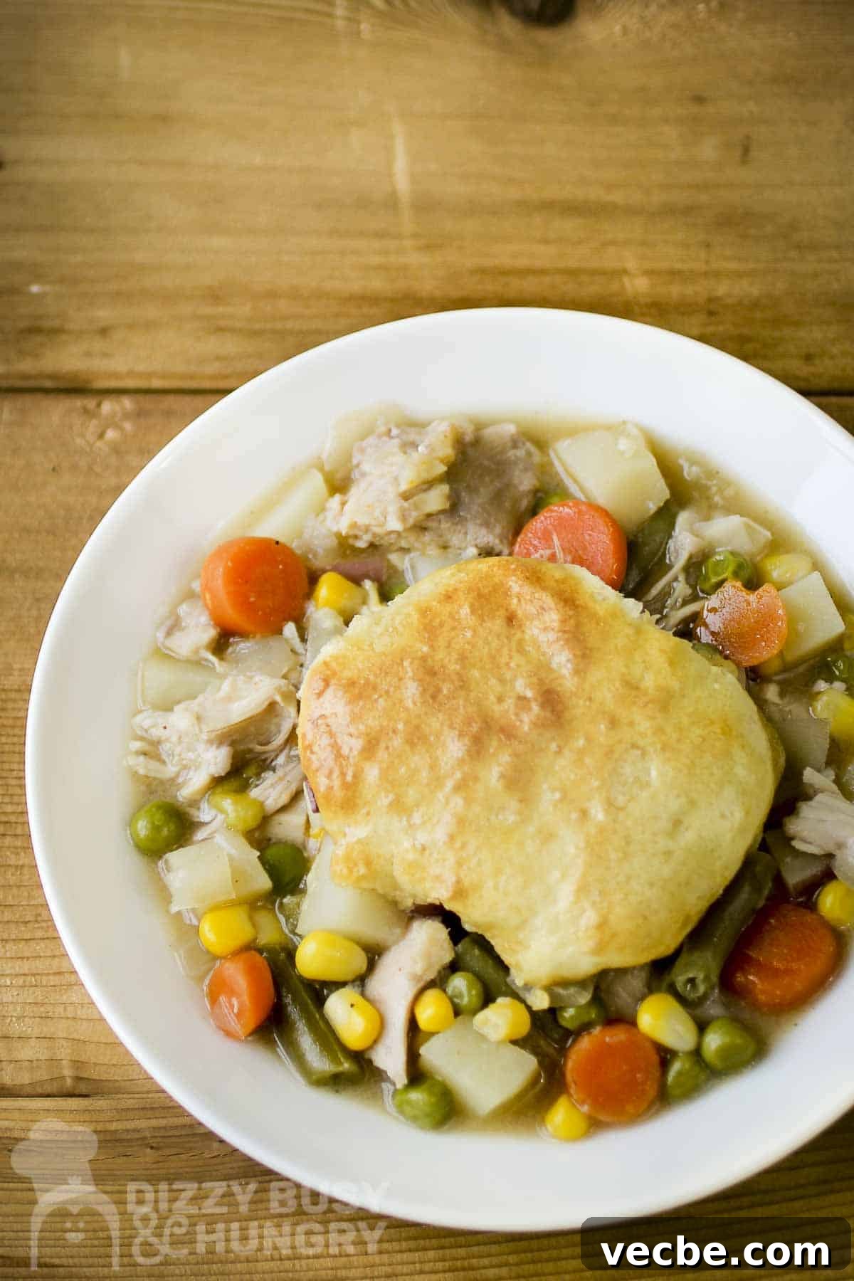 Creamy Slow Cooker Chicken and Biscuits 2 Overhead shot of chicken and biscuits on a white plate on a wooden surface.
