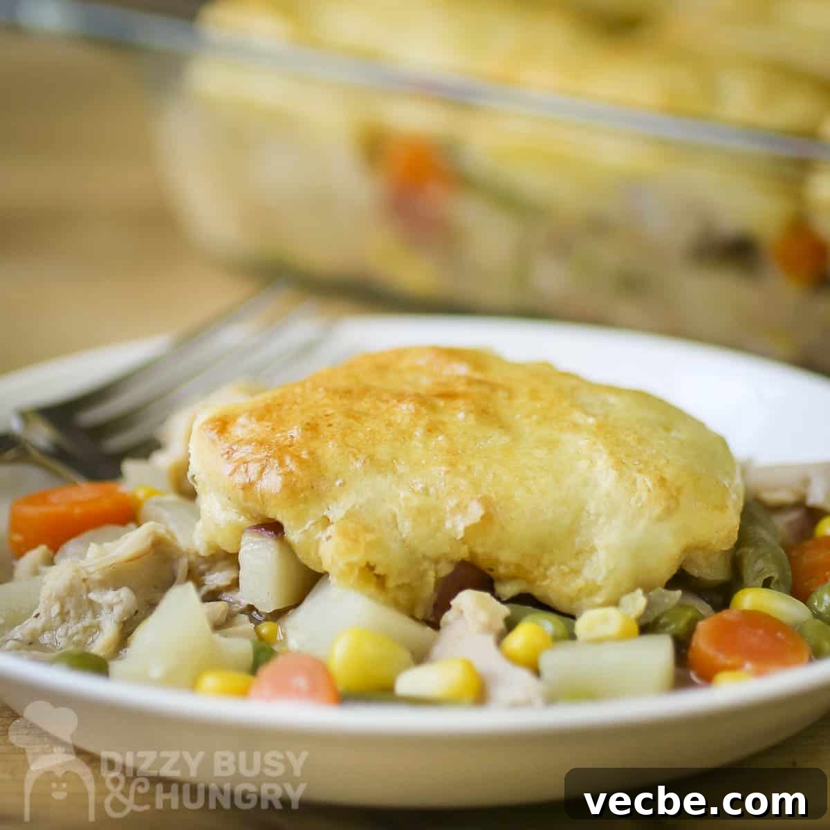 Creamy Slow Cooker Chicken and Biscuits 10 Side close up shot of chicken and biscuits on a white plate with a fork on the side.