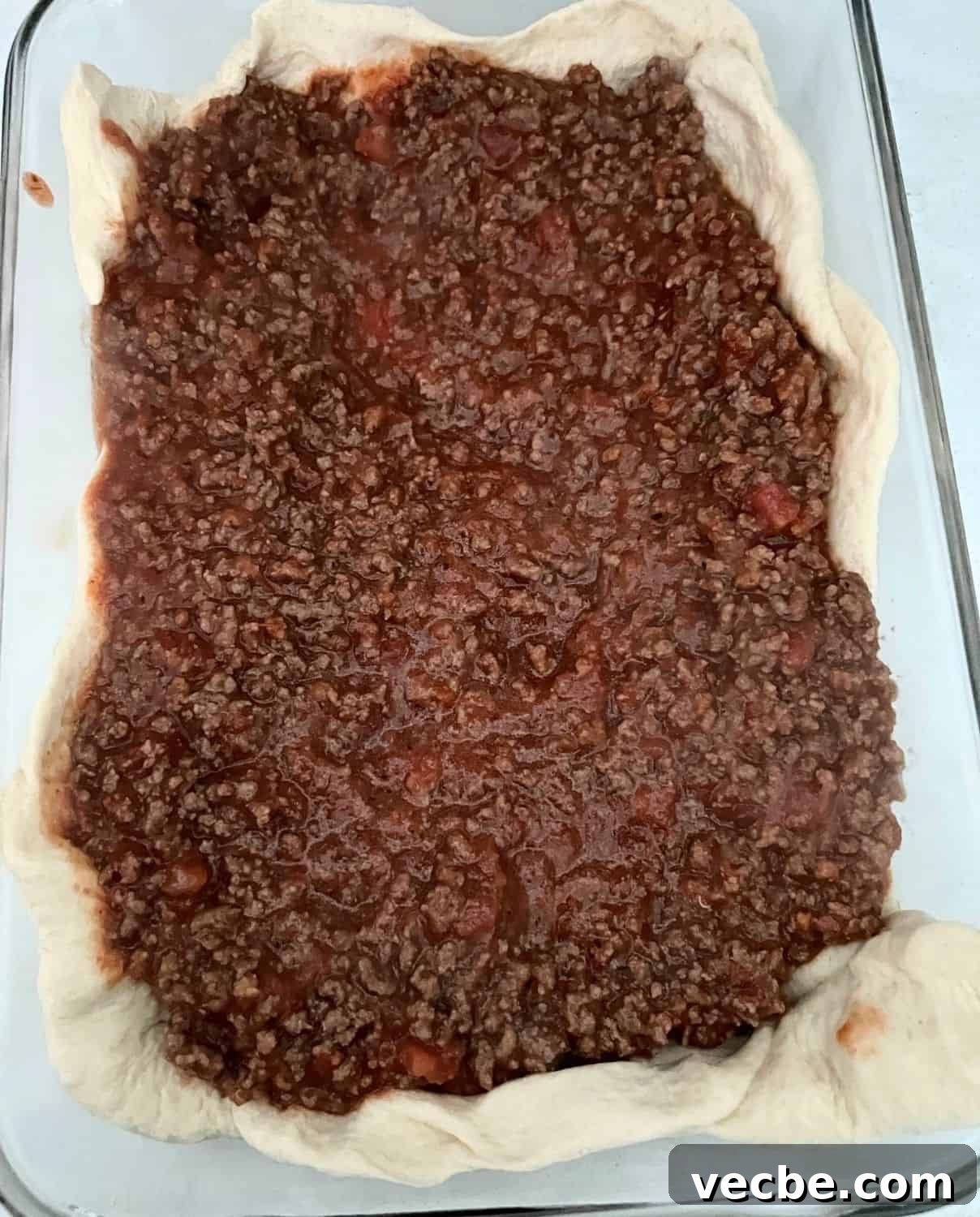 Chicago-Style Deep-Dish Pizza Casserole Recipe 5 Ground beef on top of pizza dough in a casserole pan.