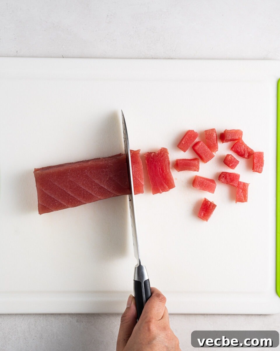 Spicy Tuna Recipe with Sriracha Mayo 4 Cutting sushi grade tuna into small cubes on a cutting board.