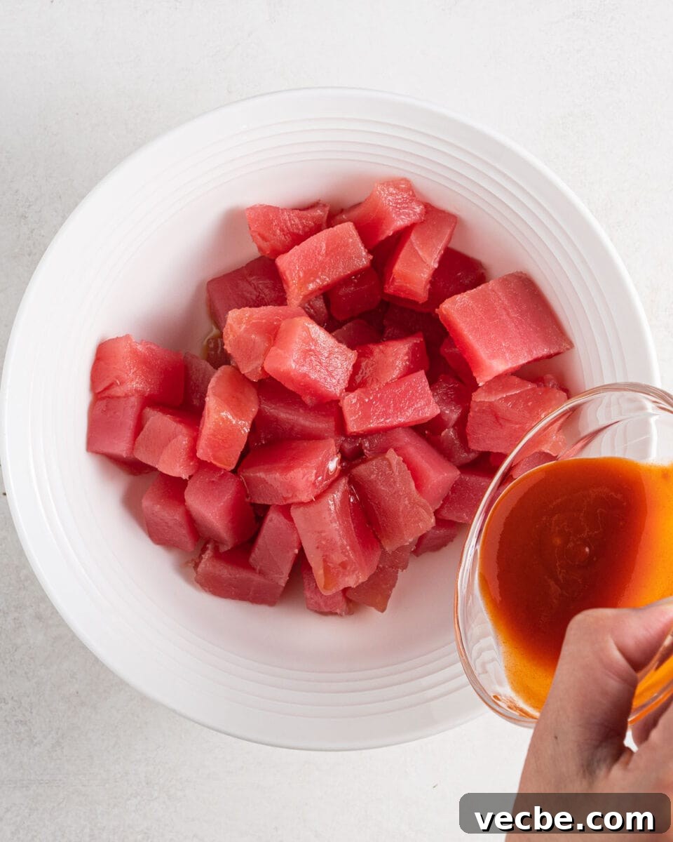 Spicy Tuna Recipe with Sriracha Mayo 5 Adding sriracha sauce to the cubes of tuna.