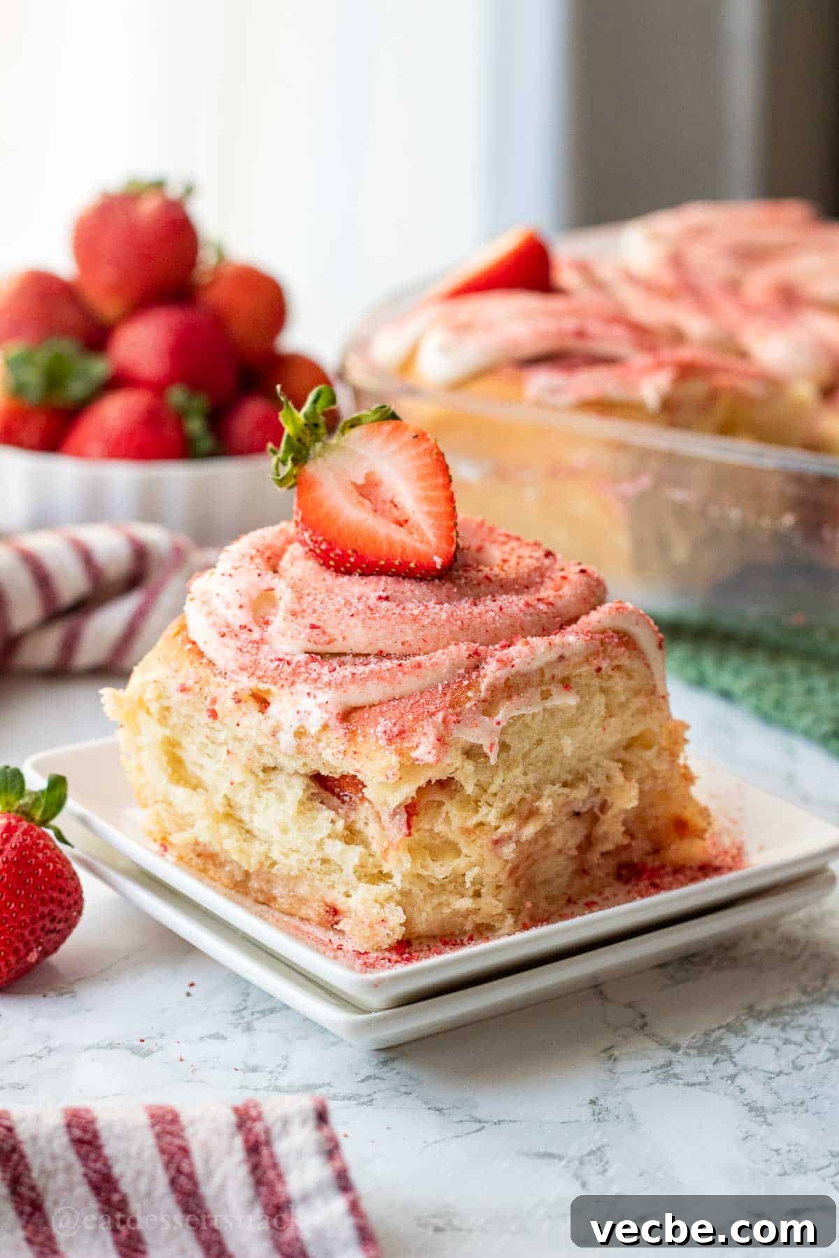 Strawberry Cheesecake Cinnamon Rolls Recipe 2 Baked strawberry cheesecake cinnamon roll on white plate.