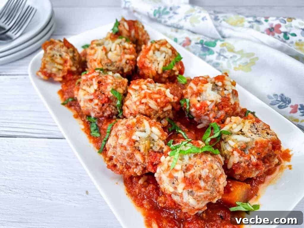 25 Ground Beef Recipes for Real Weeknight Dinners 14 A white rectangular plate with slow cooker porcupine meatballs, garnished with fresh herbs.