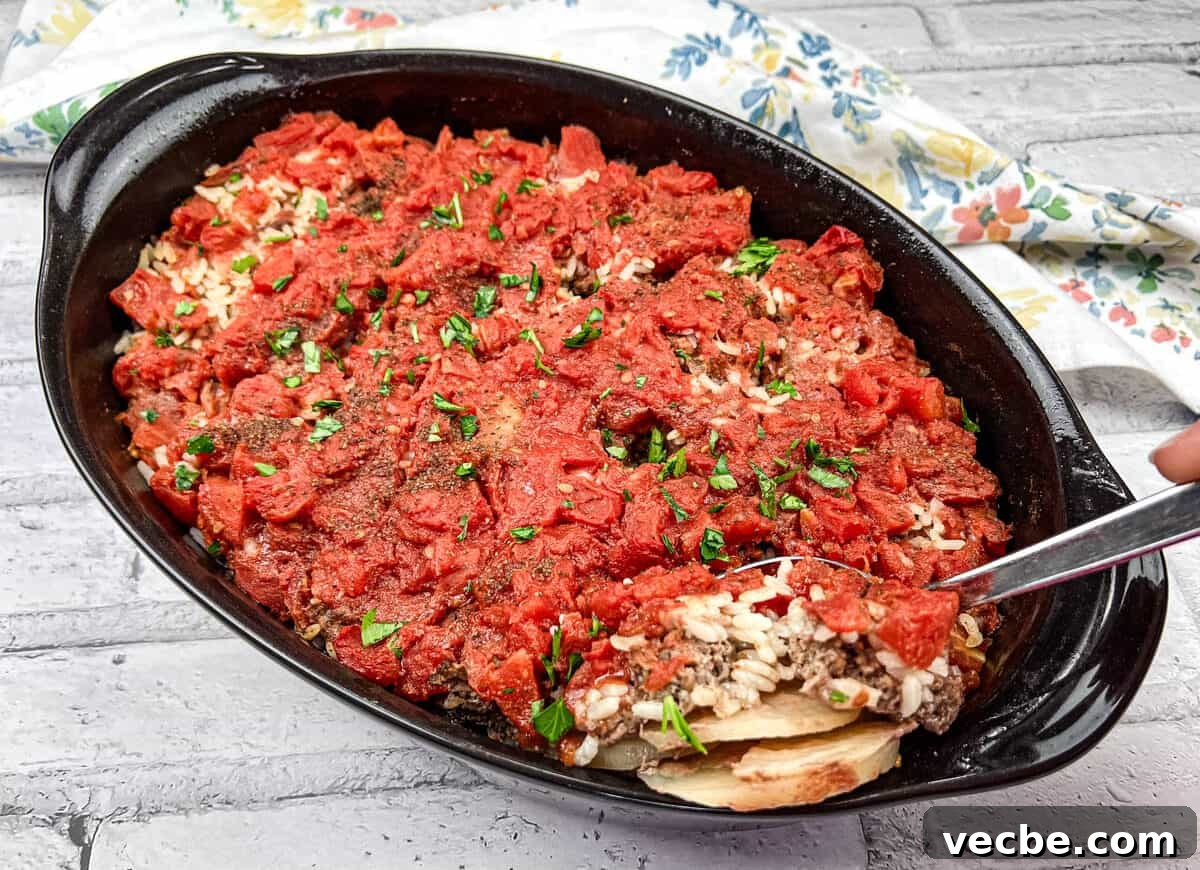 25 Ground Beef Recipes for Real Weeknight Dinners 22 Shipwreck Casserole in a black dish with a spoon.