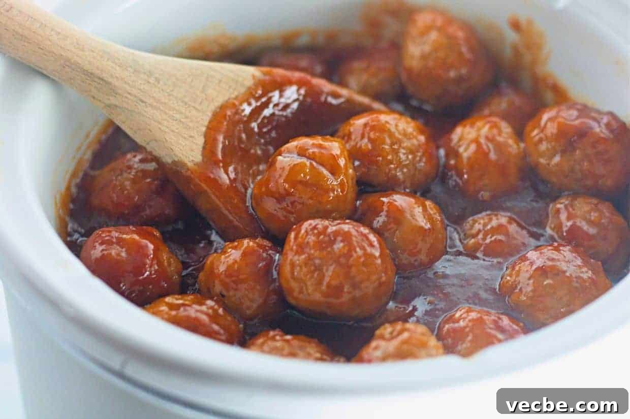 25 Ground Beef Recipes for Real Weeknight Dinners 8 Honey-Garlic Meatballs in a thick red sauce are being stirred with a wooden spoon in a white ceramic pot.