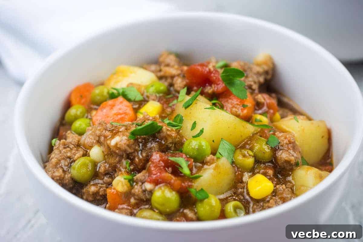 25 Ground Beef Recipes for Real Weeknight Dinners 9 A white bowl filled with easy Hamburger stew garnished with parsley.