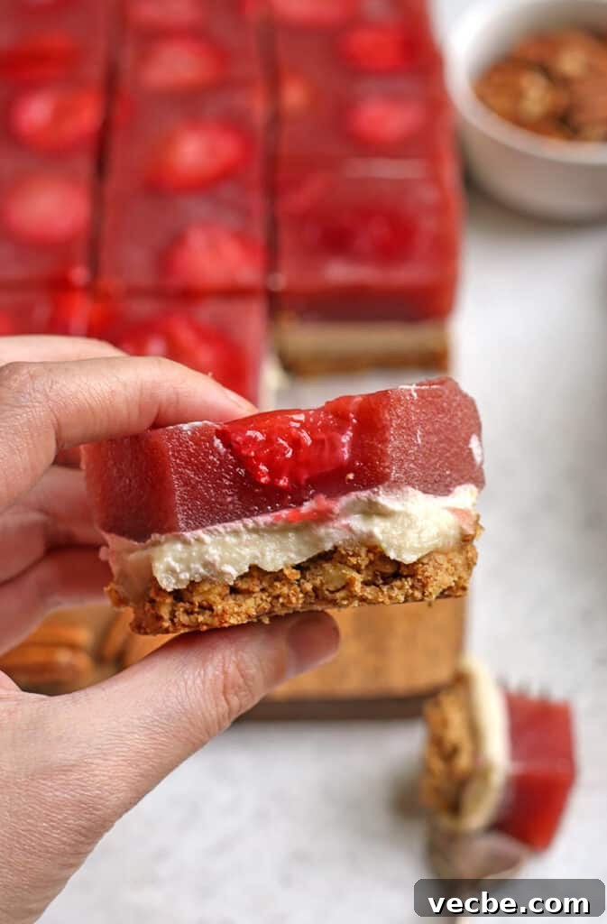 No Bake Paleo Strawberry Pretzel Salad Recipe 7 hand holding a piece of paleo strawberry pretzel salad with a bite taken out