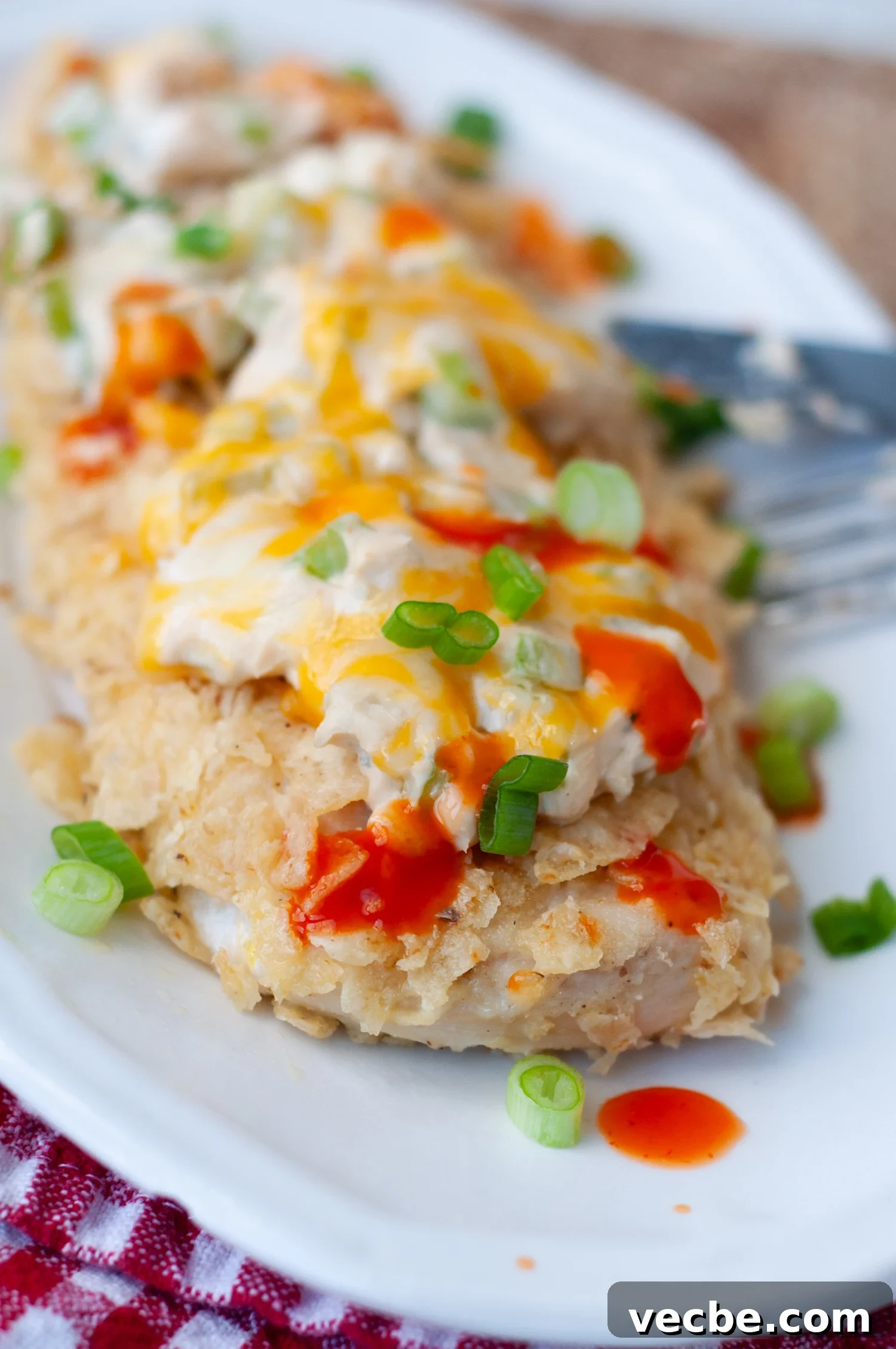 Buffalo Chicken Bake with Tortilla Chip Crust 2 a serving of chicken with crushed tortilla chips and hot sauce drizzled over top.