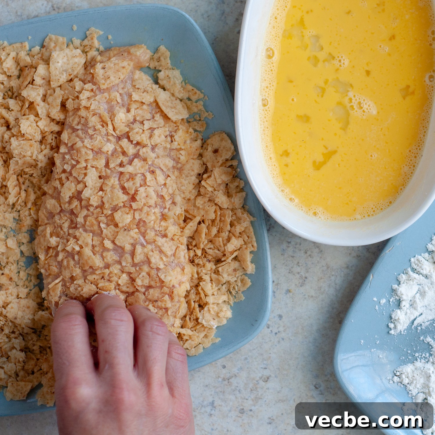 Buffalo Chicken Bake with Tortilla Chip Crust 6 chicken being dredged in crushed tortilla chips.