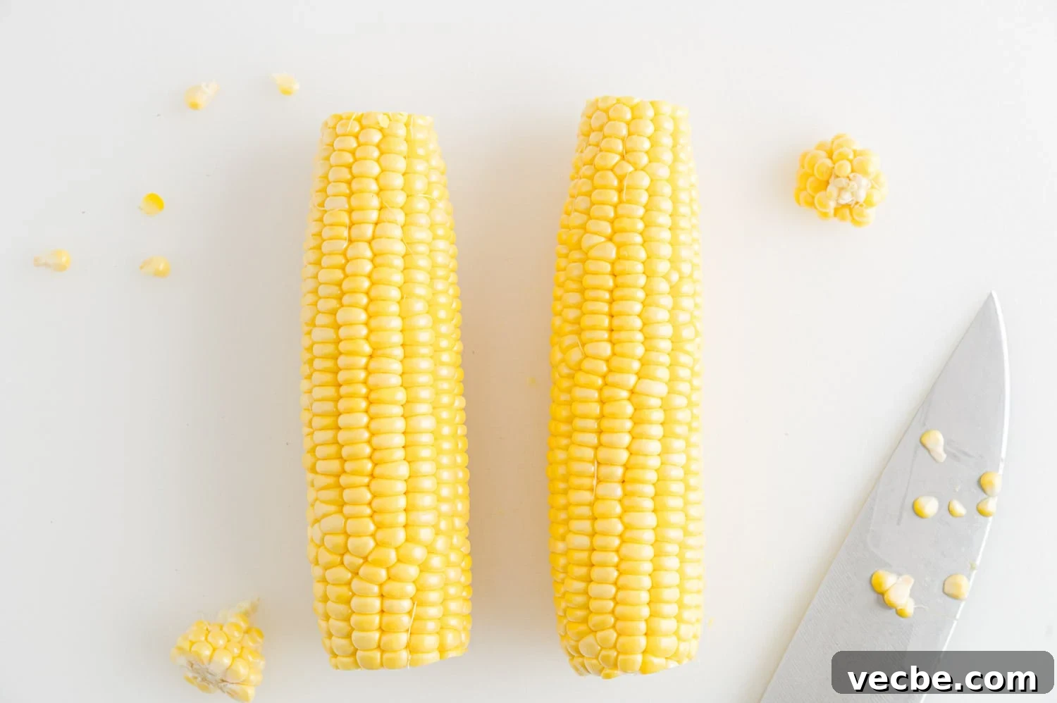 Crispy Buttered Air Fryer Corn on the Cob 3 Two ears of corn with the tips trimmed off, next to a sharp knife.