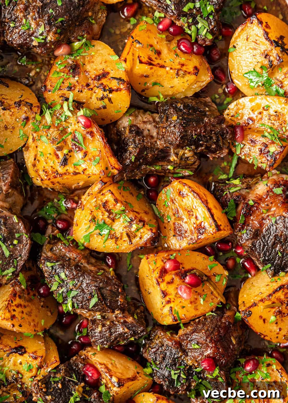 Greek Lemon Pot Roast with Crispy Potatoes 3 extreme closeup: roasted beef chuck with potatoes, herbs, and pomegranate