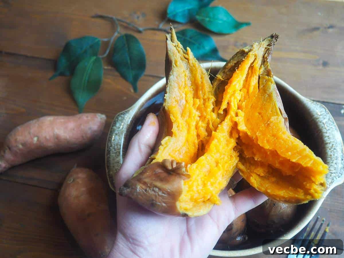 How to Cook Sweet Potatoes in the Instant Pot 2 A hand holding a cooked sweet potato over a brown bowl.