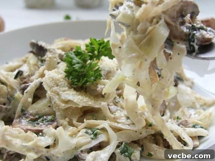 A plate of creamy cabbage fettuccine pasta with mushrooms and a garnish of parsley.