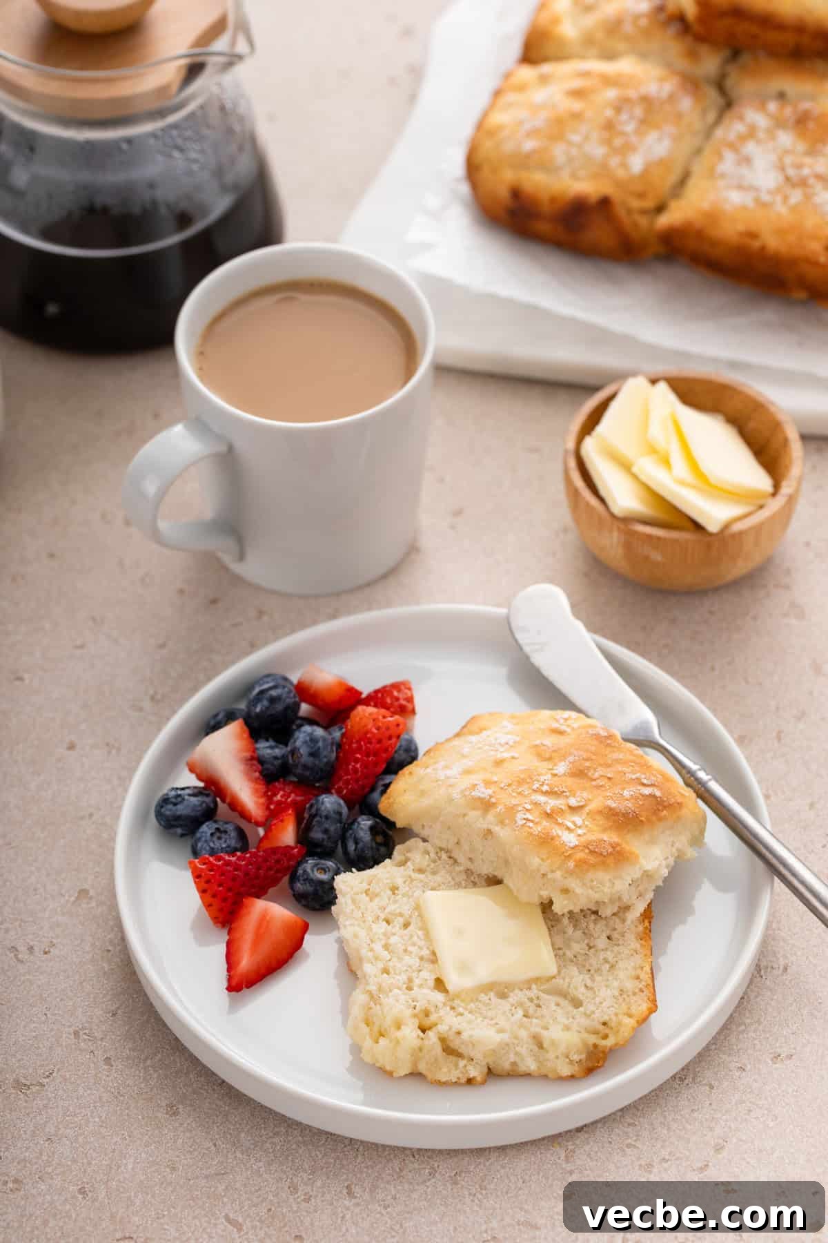 Fluffy 7-Up Biscuits Recipe 10 Buttered 7up biscuit next to fresh berries on a white plate.
