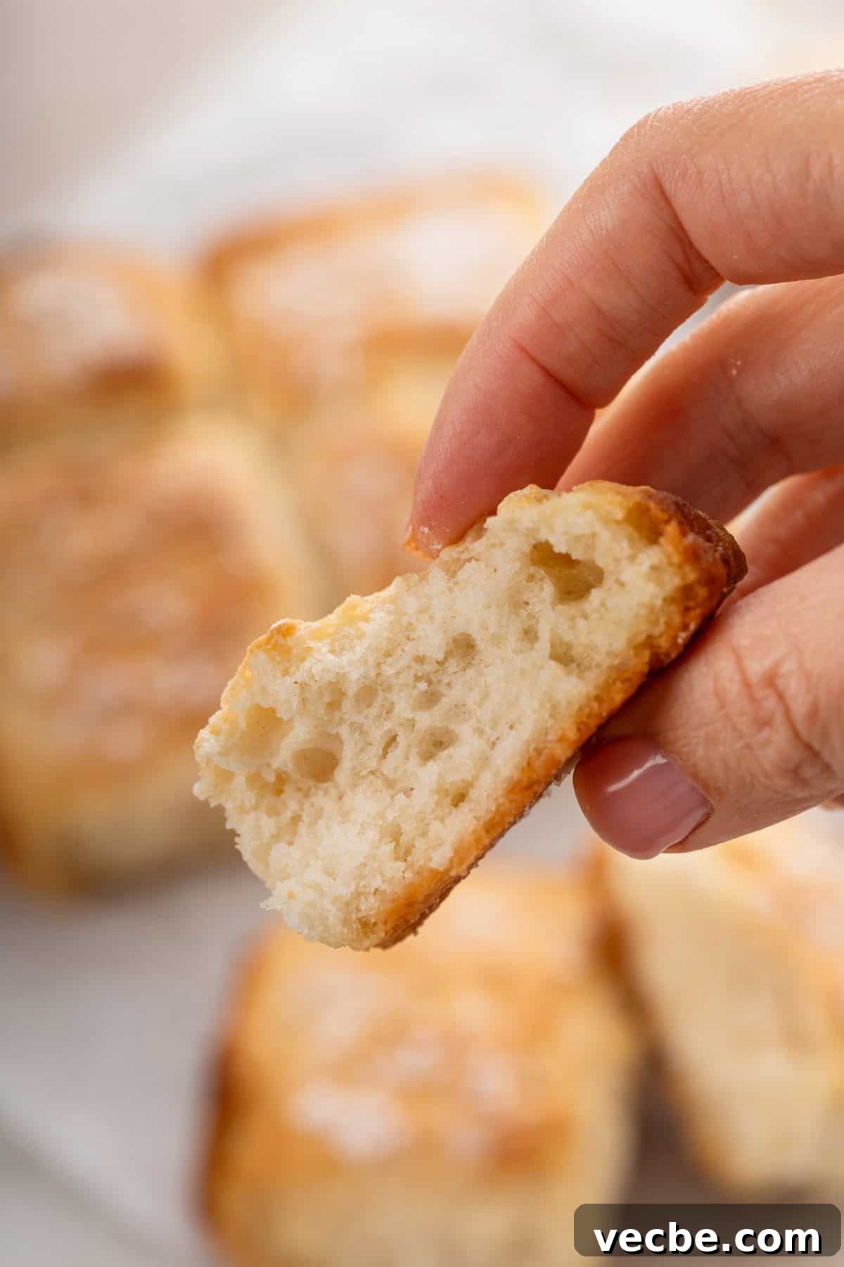 Fluffy 7-Up Biscuits Recipe 4 Hand holding part of a 7up biscuit up to the camera.