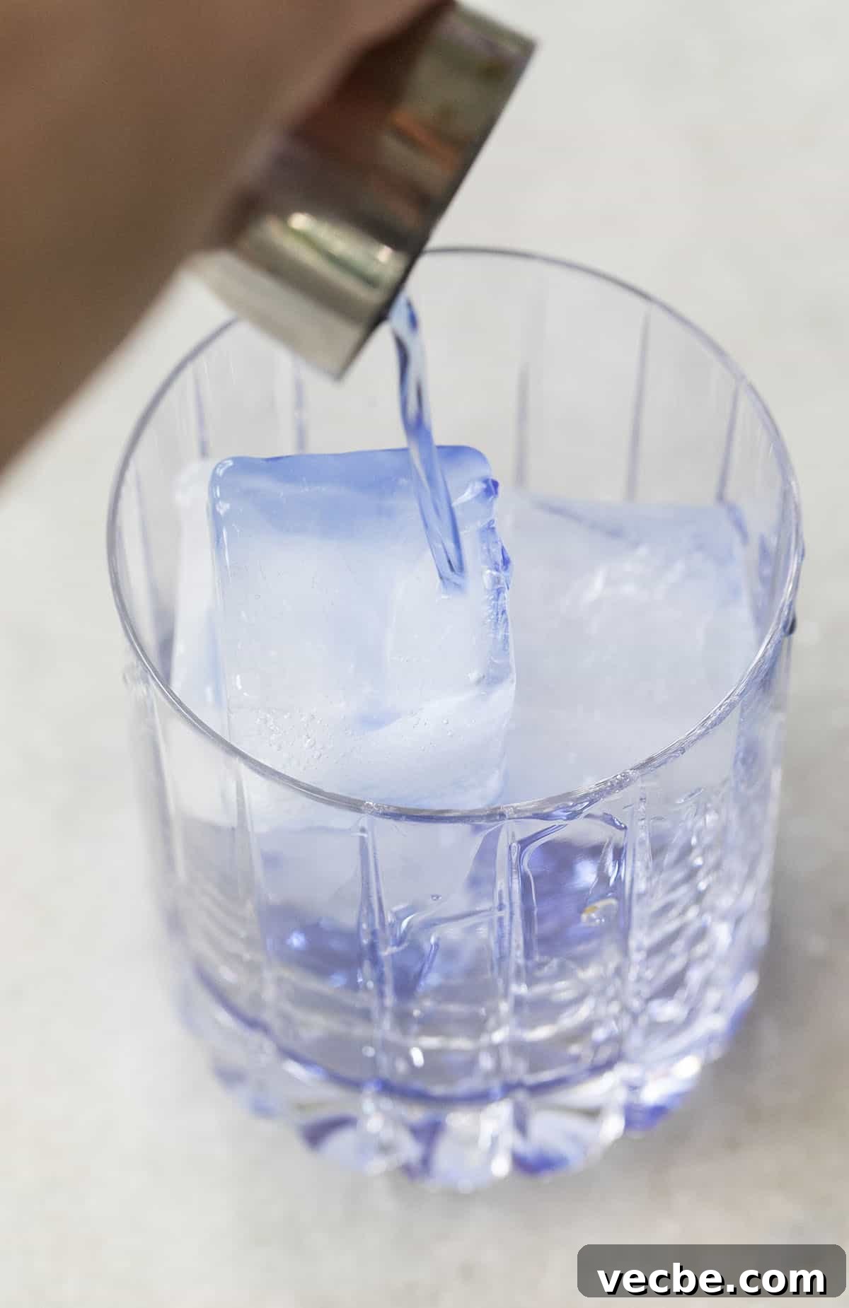 Empress Gin Cocktail Recipes to Try Tonight 6 pouring blue spirit into a glass filled with ice